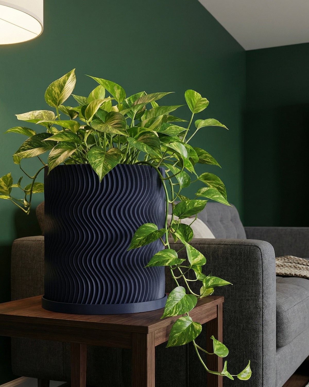 A vibrant pothos plant cascades from a stylish, dark blue planter with a unique, wavy design, set on a wooden side table.