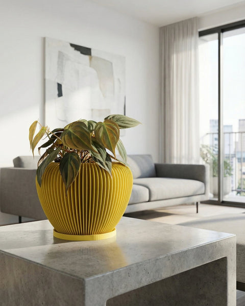 A yellow planter pot with a green plant sits on a gray concrete table in a modern living room.